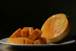 half a mango and mango pieces in a plate